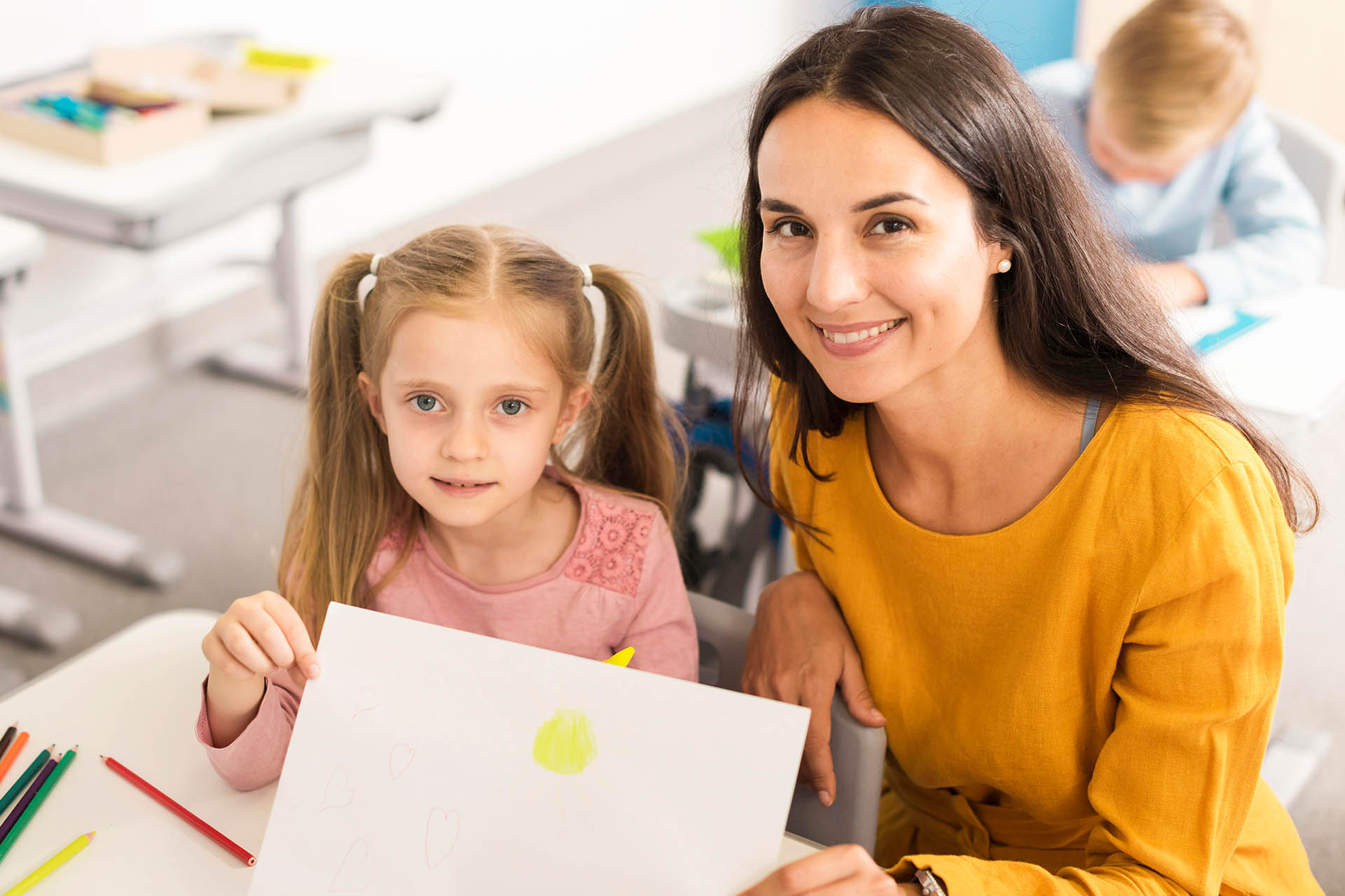 high-angle-kid-showing-her-drawing-with-her-teacher